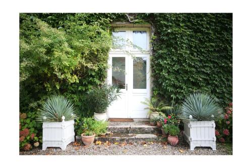 une porte d'entrée d'une maison avec des plantes en pot dans l'établissement Château d'Harcelaines, à Maisnières