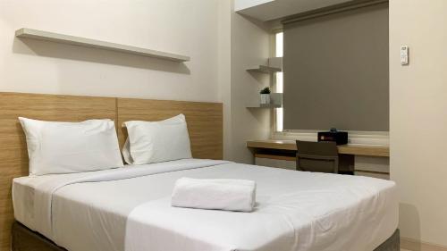 a bedroom with a large white bed with a desk at Comfort Studio Room at Margonda Residence 5 Apartment By Travelio in Depok