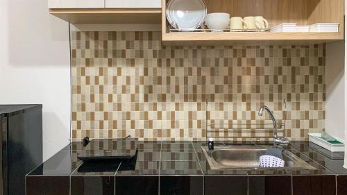 a kitchen with a sink and a tiled wall at Comfort Studio Room at Margonda Residence 5 Apartment By Travelio in Depok