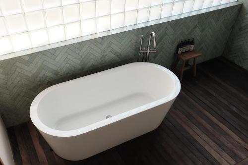 a bath tub with a faucet in a bathroom at New Little Ripper Boutique Hotel in Tanah Lot