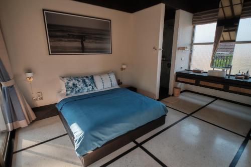 a bedroom with a bed with blue sheets and a window at New Little Ripper Boutique Hotel in Tanah Lot