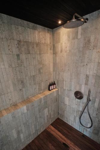 a shower in a bathroom with a tile wall at New Little Ripper Boutique Hotel in Tanah Lot