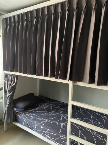 a bunk bed with black curtains in a room at Jomtien Beach Hostel & Guesthouse in Jomtien Beach