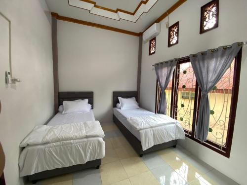 two beds in a room with a window at De Papel Homestay in Kota Bawah Timur