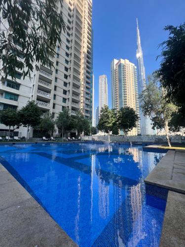 a blue swimming pool in a city with tall buildings at Luxury High Floor 1BR with Full Burj Khalifa View by Auberge in Dubai
