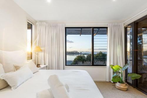une chambre avec un grand lit blanc et une grande fenêtre dans l'établissement Currumbin Beachside Retreat, à Gold Coast