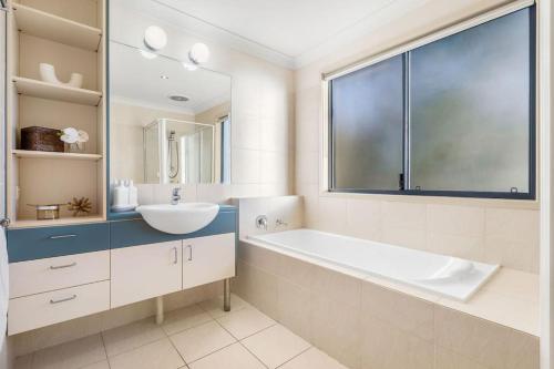 une salle de bain avec une baignoire, un lavabo et une fenêtre dans l'établissement Currumbin Beachside Retreat, à Gold Coast