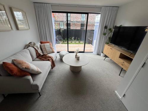 a living room with a couch and a tv and a table at Luxury And Serene 2 Bed Near CBD With Parking in Christchurch