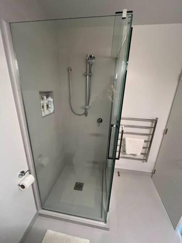 a shower with a glass door in a bathroom at Luxury And Serene 2 Bed Near CBD With Parking in Christchurch