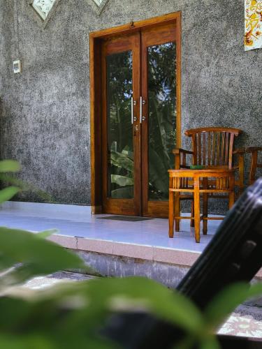 a wooden door with a chair in front of a house at Biya Lumba in Candidasa