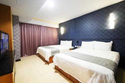 a hotel room with two beds and a television at I Hi Loveriver Hotel in Kaohsiung