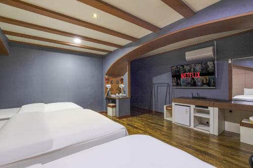 a bedroom with two beds and a tv on the wall at Hotel Tate V in Suwon