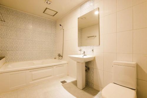 a bathroom with a sink and a toilet and a tub at Hotel Tate V in Suwon