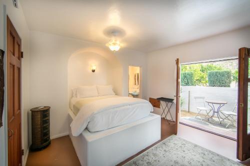 a white bedroom with a bed and a balcony at Korakia Pensione in Palm Springs