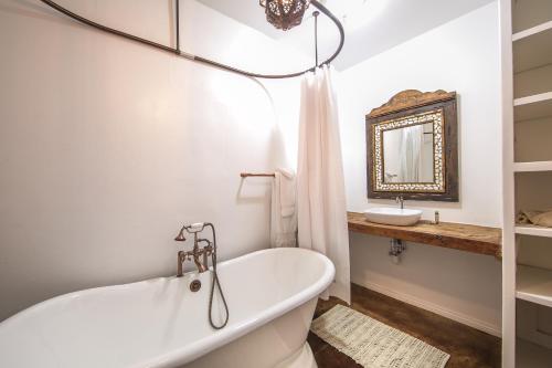 a white bathroom with a tub and a sink at Korakia Pensione in Palm Springs