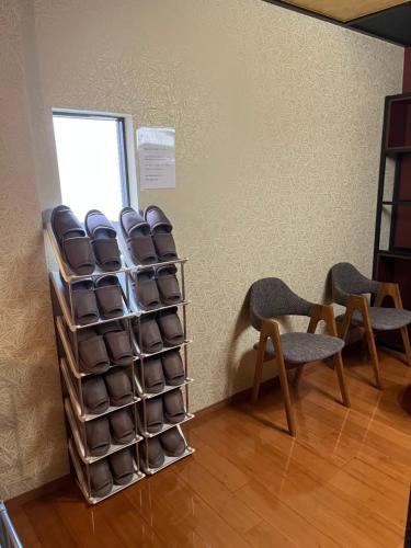 a room with two chairs and a rack of towels at Hanamachi guest house in Osaka