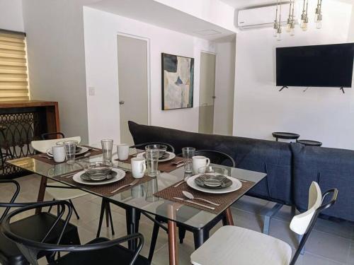 a dining room with a table and chairs and a tv at Departamento Colibrí in Playa del Carmen