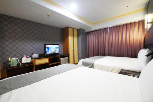 a hotel room with two beds and a television at I Hi Loveriver Hotel in Kaohsiung