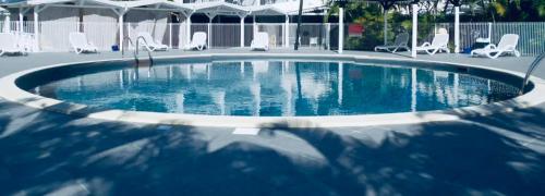 - une piscine avec des chaises blanches dans l'établissement Appart' CosyChik' Vue Golf Au Cœur De La Marina À Pied !!!, à Saint-François