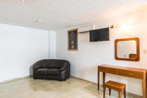 a living room with a black leather chair and a mirror at Suites Poliforum Inn in León
