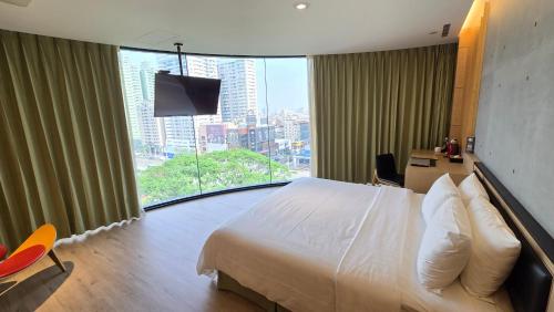 a hotel room with a bed and a large window at Hotel R14 in Kaohsiung