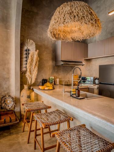 a kitchen with a counter with stools and a sink at Diwatu Villas in El Nido