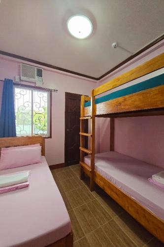 a bedroom with two bunk beds and a window at Nober Pension House City Center in Puerto Princesa City