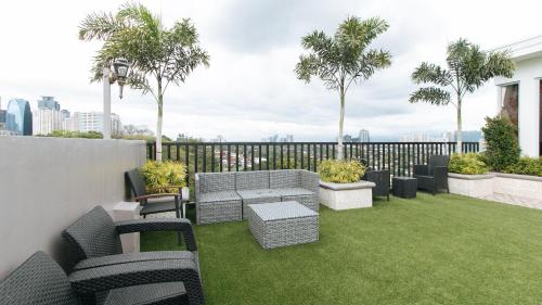 a patio with chairs and a table and grass at RedDoorz Plus at Canley Residential in Manila