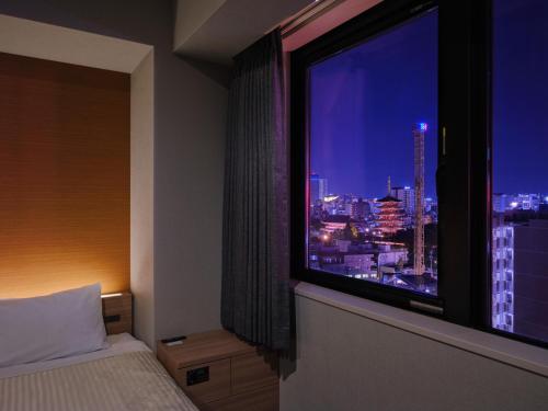 a bedroom with a window with a view of a city at hotel MONday Asakusa in Tokyo