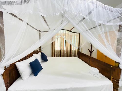 a bedroom with a canopy bed with blue and white pillows at Hamilton Mirissa in Kamburugamuwa