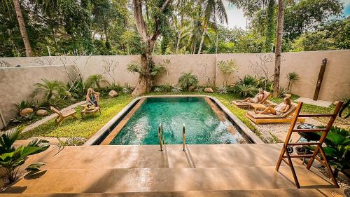 a swimming pool with two people sitting in chairs in a backyard at Diwatu Villas in El Nido