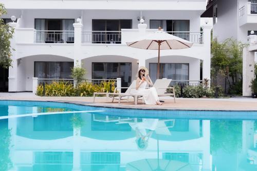 a woman sitting on a chair next to a swimming pool at Pinnacle Grand Jomtien Resort and Beach Club in Na Jomtien