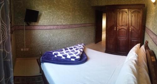 a bedroom with a bed with a wooden cabinet at Hotel Espace Tifawine in Tafraoute