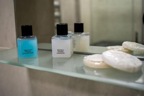 three bottles ofodorizers sitting on a counter in front of a mirror at Просторная квартира Баку in Baku