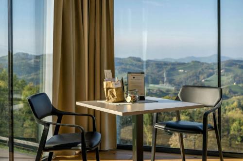 a table and two chairs in a room with a large window at WURZENBERG Hotel Lodges Südsteiermark in Gamlitz