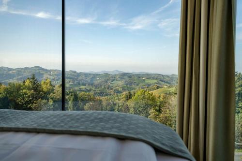 a bedroom with a view of the mountains through a window at WURZENBERG Hotel Lodges Südsteiermark in Gamlitz