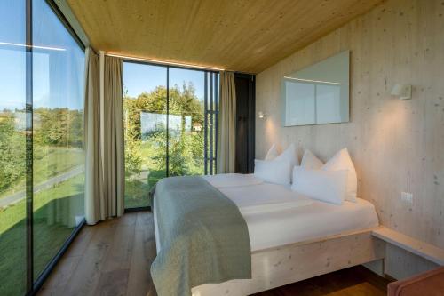 a bedroom with a large bed and large windows at WURZENBERG Hotel Lodges Südsteiermark in Gamlitz