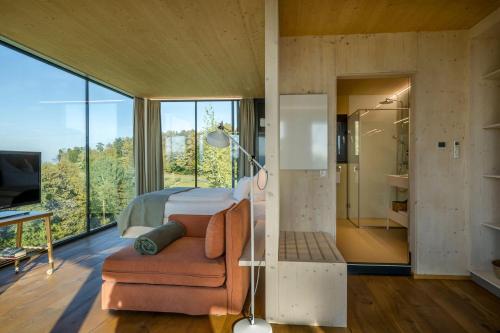 a bedroom with a bed and a chair and a shower at WURZENBERG Hotel Lodges Südsteiermark in Gamlitz