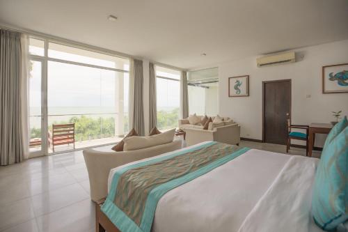 a bedroom with a large bed and a living room at The Habitat Kosgoda by Asia Leisure in Bentota