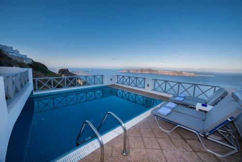 a swimming pool with a chair on a balcony overlooking the ocean at Prekas Apartments in Imerovigli