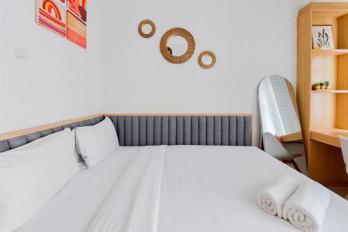 a bedroom with a white bed with two pillows at Minimalist and Strategic Studio at Serpong Garden Apartment By Travelio in Tangerang