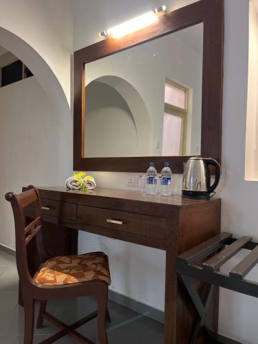 a vanity with a mirror and a chair and water bottles at Paradise Garden Beruwala in Beruwala