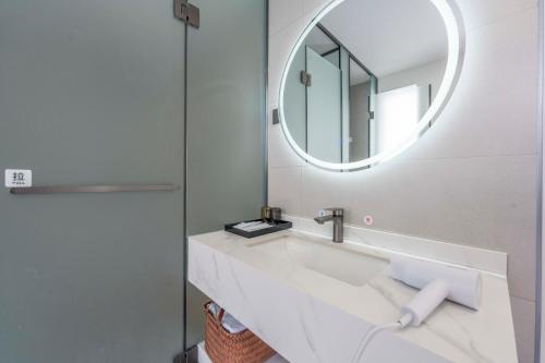 a white bathroom with a sink and a mirror at Lane Wisdom Garden Hotel - Lijiang Ancient City Zhongyi Market in Lijiang