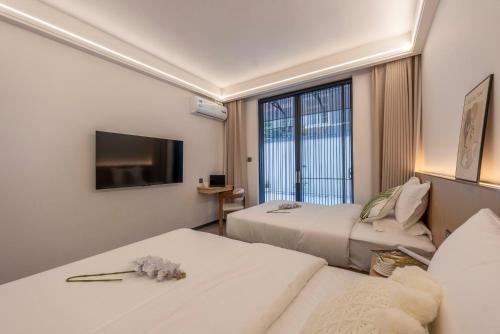 a hotel room with two beds and a flat screen tv at Lane Wisdom Garden Hotel - Lijiang Ancient City Zhongyi Market in Lijiang