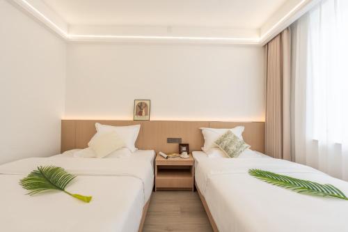 two beds in a hotel room with palm plants at Lane Wisdom Garden Hotel - Lijiang Ancient City Zhongyi Market in Lijiang