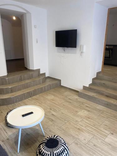 a living room with a table and a tv and stairs at Ferienwohnung Bergblick Flirsch in Flirsch
