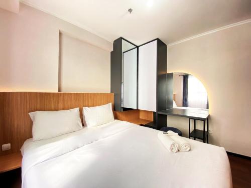 バンドンにあるNice 2BR at Gateway Pasteur Apartment By Travelioの大きな白いベッドと机のある寝室