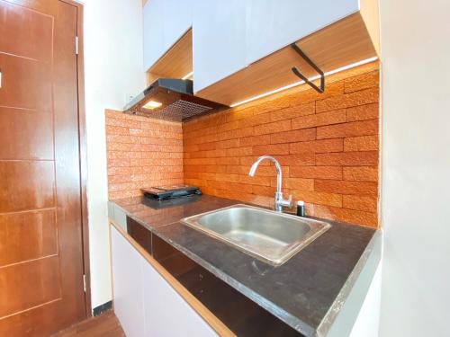 バンドンにあるNice 2BR at Gateway Pasteur Apartment By Travelioのシンクとレンガの壁のあるキッチン