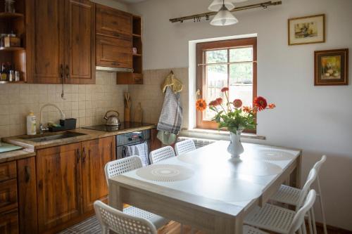 a kitchen with a table with chairs and a vase of flowers at Doberek Noclegi w Beskidzie Niskim in Kobylanka