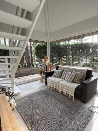 a living room with a couch and some windows at L Orée de la Pinède Hardelot Plage à 800 metres de la mer sous les pins in Hardelot-Plage